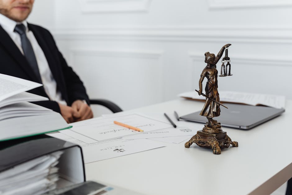 A legal professional's workspace featuring Lady Justice statue, documents, and a laptop.